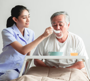 caregiver feeding senior man