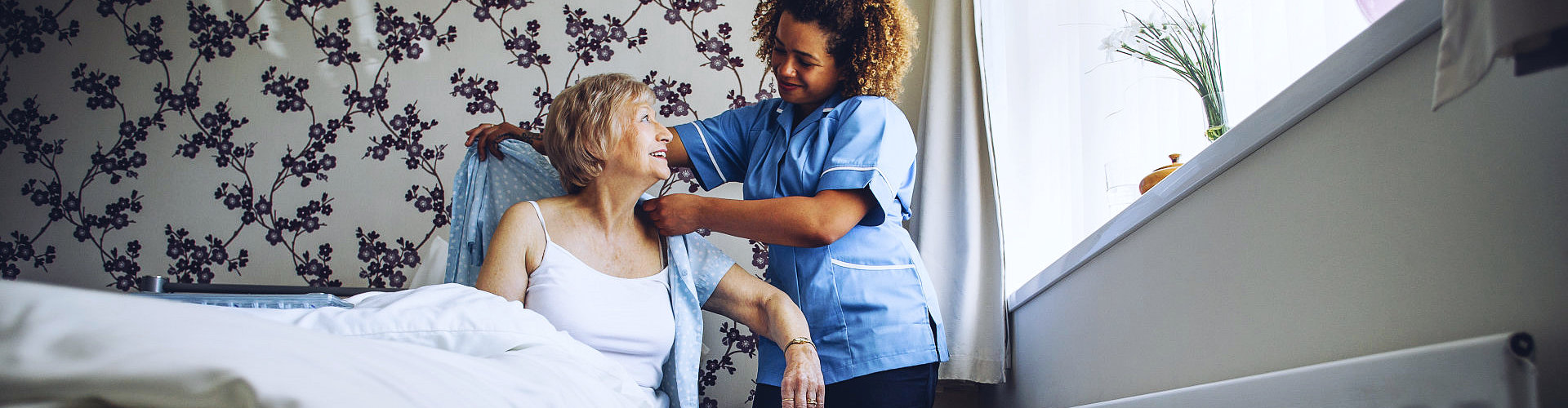 caregiver helping senior woman put on clothes